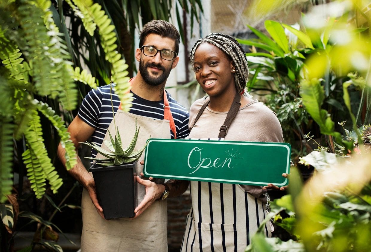 A man and woman holding plants in their hands.